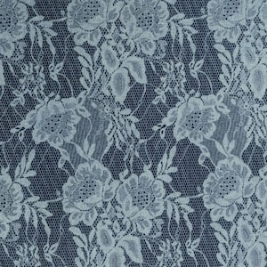 May include: A white lace fabric with a floral pattern on a dark blue background.