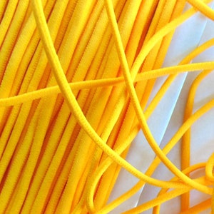 May include: A close-up of a pile of bright yellow elastic cord. The cord is soft and flexible, and it is ideal for crafting projects.