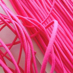 May include: A close-up of a bundle of bright pink elastic cord. The cord is soft and flexible, and it is ideal for crafting projects.