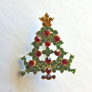 Puede incluir: Un broche de árbol de Navidad de color verde y rojo con una estrella dorada en la parte superior.