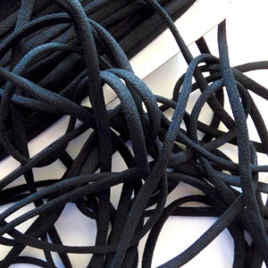 May include: A close-up of a spool of black elastic cord, with some cord unwound and tangled. The cord is a solid black colour and appears to be made of a flexible material. The cord is likely used for sewing or crafting projects.