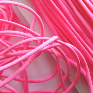 May include: A close-up of pink elastic cord, a type of string used for crafts and jewellery making.