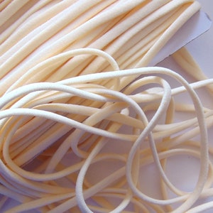 May include: A close-up of a pile of cream-coloured elastic cord. The cord is soft and flexible, and it is ideal for crafting projects.