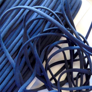 May include: A spool of navy blue elastic cord. The cord is tightly wound and is approximately 6mm thick.