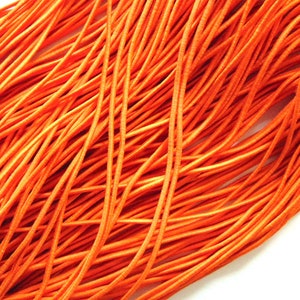 May include: Close-up of a bundle of bright orange elastic cord against a white background. The cords are tightly packed and appear to be made of a flexible, durable material, suitable for various crafting and DIY projects.