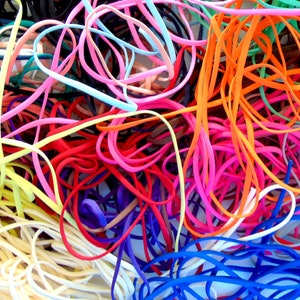 May include: A jumbled collection of colourful elastic cords in various shades of pink, orange, yellow, blue, green, and black.