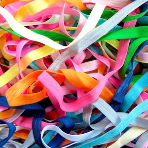 May include: A collection of colorful elastic bands in various shades of blue, green, pink, orange, yellow, and white. The bands are tangled together, creating a vibrant and textured background.