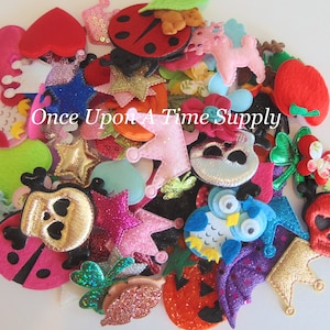 May include: A collection of colourful felt appliques, including stars, crowns, owls, ladybugs, skulls, and pumpkins. The appliques are perfect for adding a touch of whimsy to crafts, clothing, and home decor. "Once Upon A Time Supply" is written on the image.