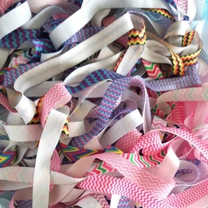 May include: A pile of colorful elastic ribbon with zig-zag patterns. The ribbon is in various colors, including pink, blue, white, and black.