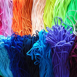 May include: A collection of colourful elastic cords in various shades of pink, orange, green, blue, purple, and white. The cords are arranged in rows and are all the same width.