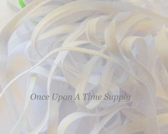 May include: A close-up of white elastic ribbon, both coiled and loose, against a white background. The elastic is tightly woven and appears to be new. The text "Once Upon A Time Supply" is visible.