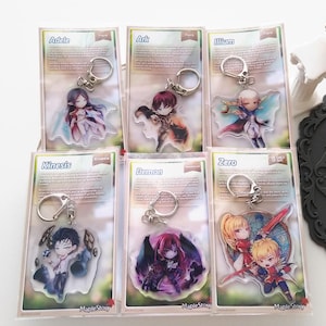 May include: Six acrylic keychains featuring anime-style characters from the game MapleStory. Each keychain has a different character design, with a silver keyring attached. The keychains are packaged in clear plastic with character information.