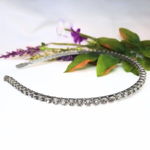 May include: A silver headband with a row of clear rhinestones.