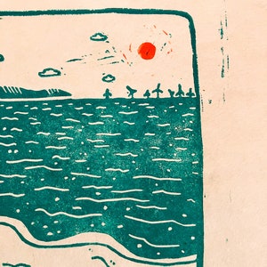 Linoprint of two wild swimmers enjoying pastries on the beach. Close up of the sun. Printed in turquoise ink with a red sun.