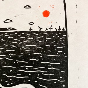 Linoprint of two wild swimmers enjoying pastries on the beach. Close up of the sun. Printed in black ink with a red sun.