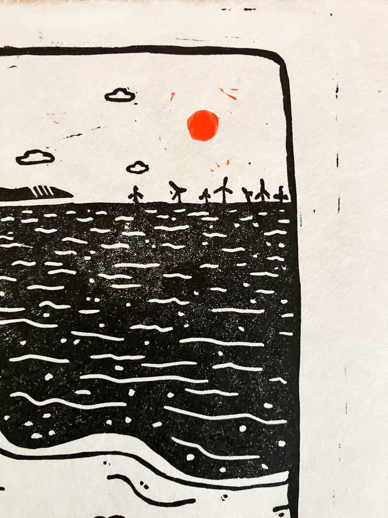 Linoprint of two wild swimmers enjoying pastries on the beach. Close up of the sun. Printed in black ink with a red sun.