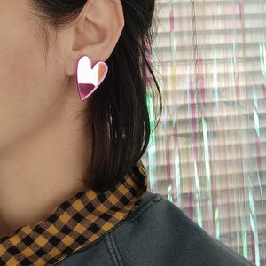 May include: A pair of pink heart-shaped earrings with a mirrored finish.