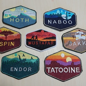 Puede incluir: Siete parches bordados que representan diferentes planetas del universo de Star Wars. Cada parche es hexagonal y presenta el nombre de un planeta diferente, así como una imagen estilizada del planeta. Los planetas son Hoth, Naboo, Bespin, Mustafar, Jakku, Endor y Tatooine.