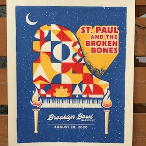 May include: A blue and yellow concert poster with a stylized piano design. The text reads "St. Paul and the Broken Bones" and "Brooklyn Bowl Nashville, August 28, 2020".