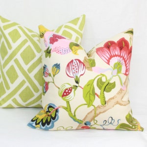 May include: Two decorative throw pillows, one with a green and white geometric pattern and the other with a floral pattern featuring pink, red, yellow, and green flowers on a cream background.