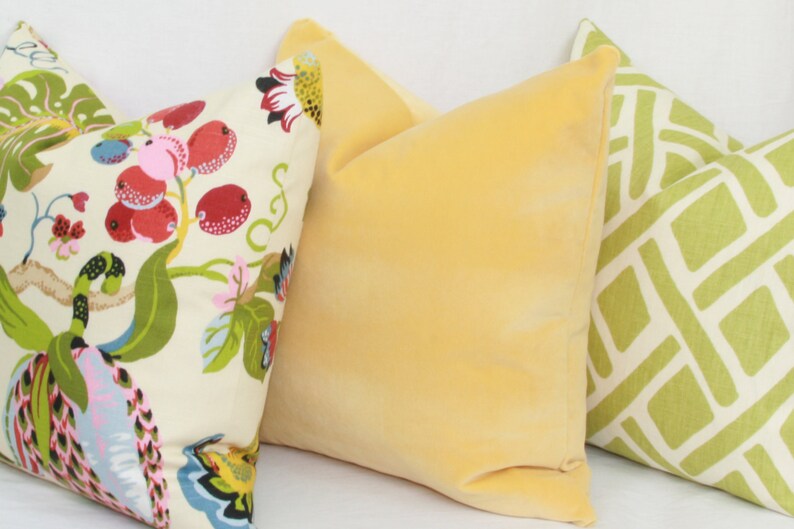 May include: Three decorative throw pillows. One pillow has a floral pattern with red, pink, and green accents. Another pillow is a solid yellow. The third pillow has a geometric pattern with green and white accents.