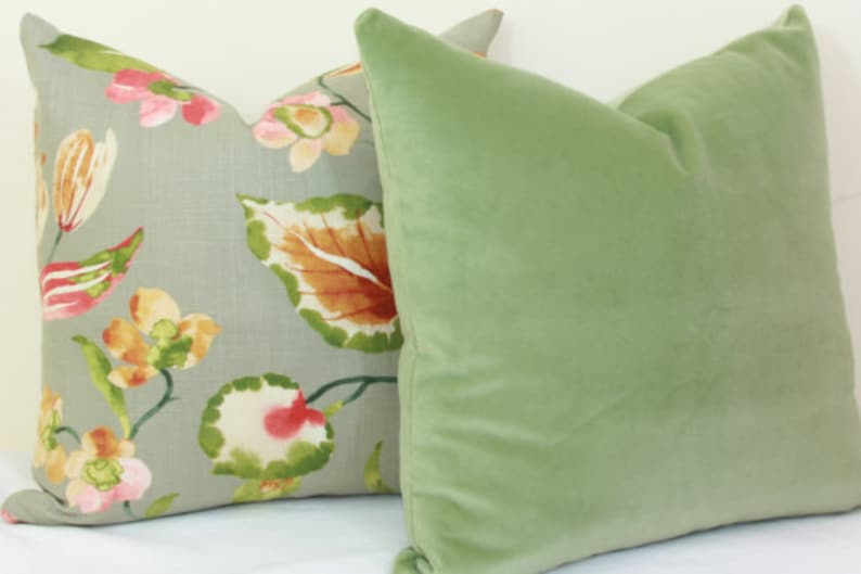 May include: Two decorative throw pillows, one with a floral pattern on a light gray background and the other a solid sage green.