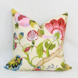 May include: A cream-colored pillow with a floral pattern. The flowers are pink, red, yellow, and green. The pillow is made of fabric and has a square shape.