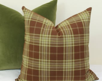 May include: A brown and green plaid pillow with a solid green velvet pillow behind it.