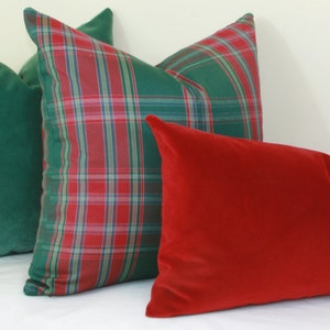 May include: Three decorative throw pillows. One is a solid green velvet, one is a red velvet, and one is a plaid pattern with red, green, and blue.