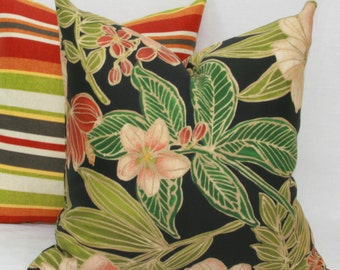 May include: Two decorative throw pillows. One pillow has a black background with a floral pattern in shades of green, pink, and gold. The other pillow has a striped pattern in shades of orange, green, and brown.