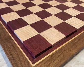 Tablero de ajedrez en relieve de madera de corazón púrpura y arce rizado con borde de maderas variadas.