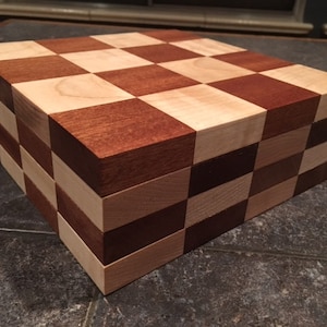 May include: A wooden chessboard with a checkerboard pattern of light and dark wood squares. The board is stacked in a pile, showing the alternating pattern of the wood.