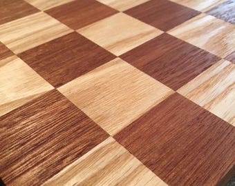 May include: A wooden chessboard with alternating light and dark squares. The board is made of two different types of wood, creating a natural pattern.
