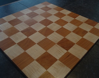 May include: A wooden chessboard with alternating light and dark squares. The board is made of light wood and dark wood.
