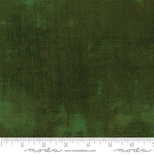 May include: A dark green fabric with a textured, distressed look. The fabric has a subtle, uneven pattern throughout. The fabric is shown with a ruler, with the text "moda" printed on the ruler.