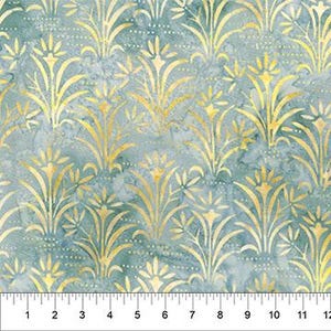 May include: A fabric with a repeating pattern of gold floral designs on a mottled teal background. The pattern is measured with a ruler showing inches from 1 to 12.
