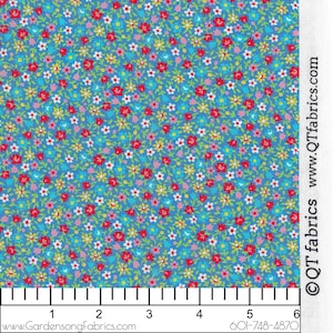 May include: A blue fabric with a small floral print featuring red, white, yellow, and pink flowers. The fabric is measured with a ruler showing 6 inches.