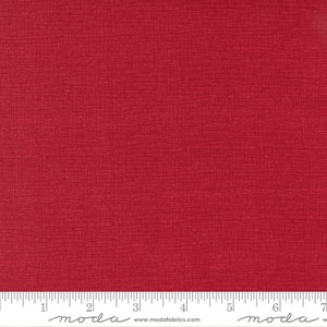 May include: A solid red fabric with a subtle textured pattern. The fabric is measured in inches with the text "moda" printed on the ruler.