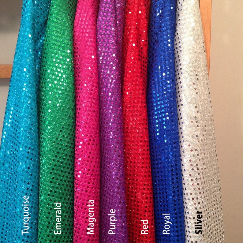 Pode incluir: Sete rolos de tecido de lantejoulas em diferentes cores: turquesa, esmeralda, magenta, roxo, vermelho, azul royal e prata.