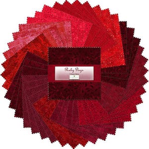 May include: A collection of red fabric squares arranged in a circular pattern. The fabric pieces vary in shades of red, from light pink to deep burgundy, with various patterns. The center features a label that reads "Ruby Days".