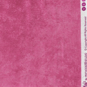 May include: A close-up of a pink fabric with a textured, slightly mottled appearance. The fabric is measured in inches with a ruler.