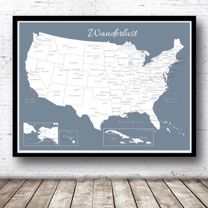 Puede incluir: Un mapa de los Estados Unidos en azul y blanco con la palabra "Wanderlust" en la parte superior. El mapa incluye los estados, las principales ciudades y las masas de agua. El mapa est&aacute; enmarcado en un marco negro.