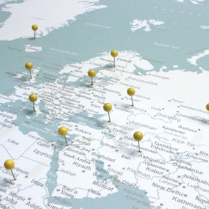 Può includere: Una mappa del mondo con puntine gialle che segnano posizioni in Europa, Asia e Africa. La mappa è stampata su uno sfondo blu chiaro.