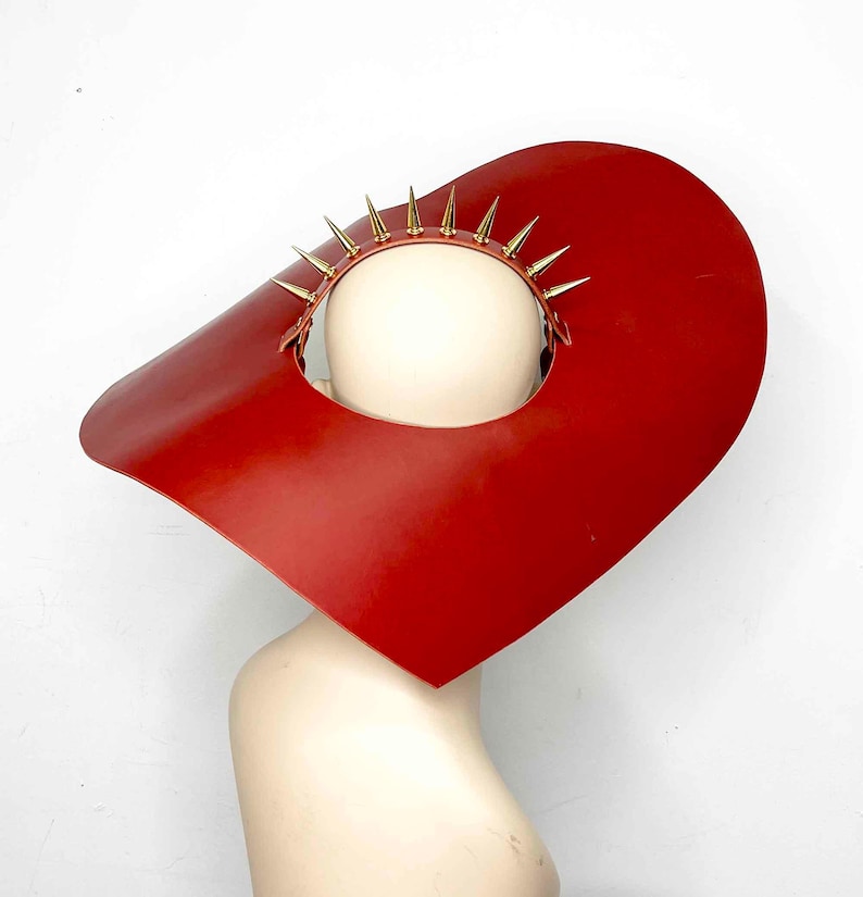May include: A red leather hat with a wide brim and a gold spiked crown.