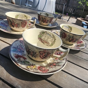 May include: Four vintage teacups and saucers with a floral pattern. The cups and saucers are white with brown, pink, and green floral designs. The cups have a scalloped edge.