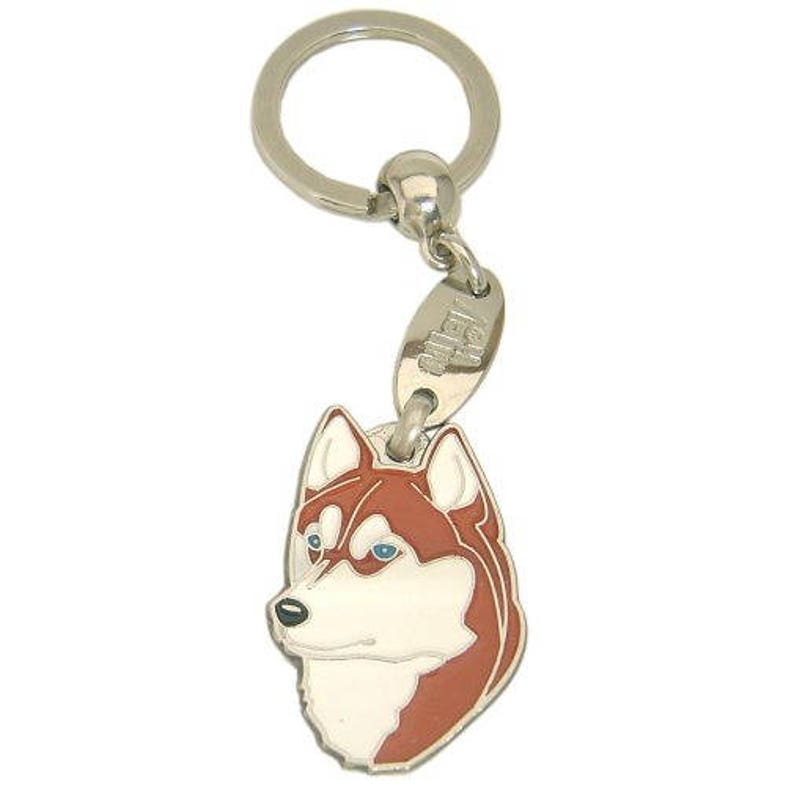 May include: A silver-toned keychain featuring a pendant shaped like a Husky dog's head. The pendant has a white face, brown markings, and blue eyes. The keychain includes a split ring and a small tag.