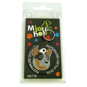 May include: A black dog tag featuring an Australian Cattle Dog illustration, with the text "AUSTRALIAN CATTLE DOG" and "Mjavi ho". The tag is packaged in a clear plastic holder with a metal ring for attachment. Paw prints in various colors decorate the background.