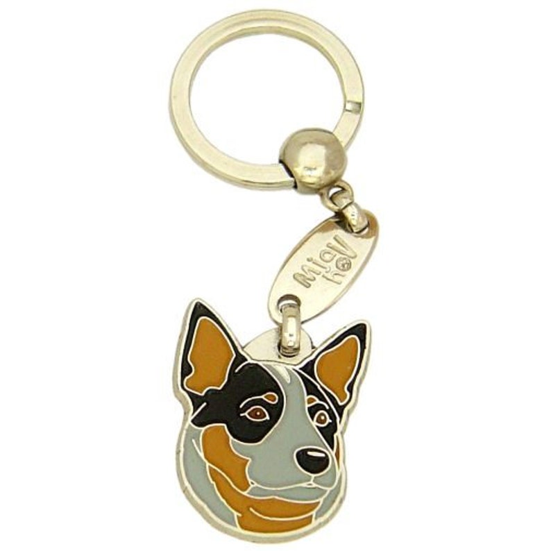May include: A gold-colored metal keychain featuring a dog's head pendant. The pendant is a detailed, colorful illustration of a dog's face with black, tan, and gray markings. The keychain includes a split ring and a small tag with text.