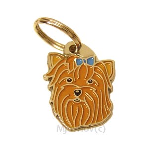 Puede incluir: Chapa de perro de metal dorado con un Yorkshire Terrier con un lazo azul. El perro est&aacute; representado con un pelaje marr&oacute;n claro y una nariz negra.