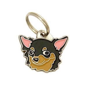 May include: A metal pet tag featuring a Chihuahua dog face. The tag has a black and tan face with pink ears and a silver-colored metal ring for attachment. The dog's face is outlined in black.